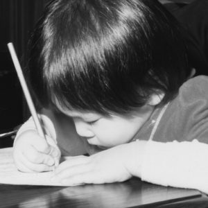 A baby picture of Mandy Lau, writing on a piece of paper