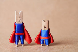 Two clothespins, dressed as superheros with red capes.